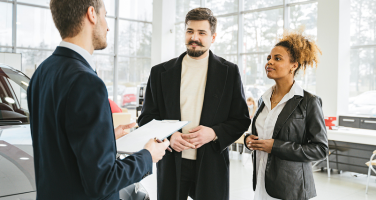 A Car Salesman Talking To A Couple At An Auto Dealership