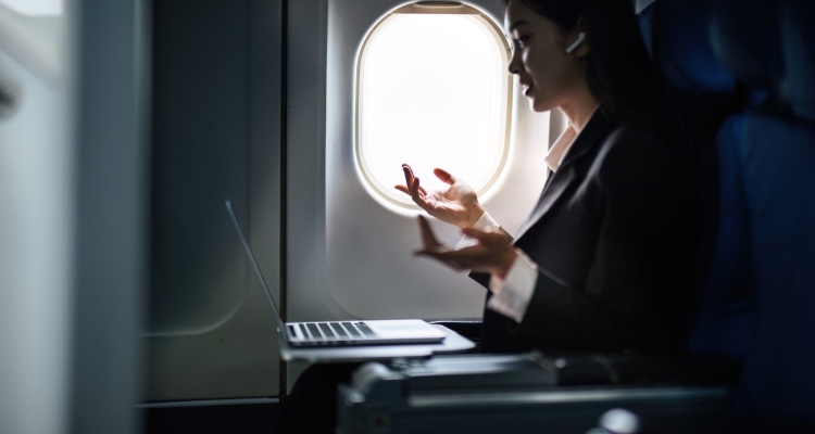 Businesswoman On Airplane Talking Into Earphone