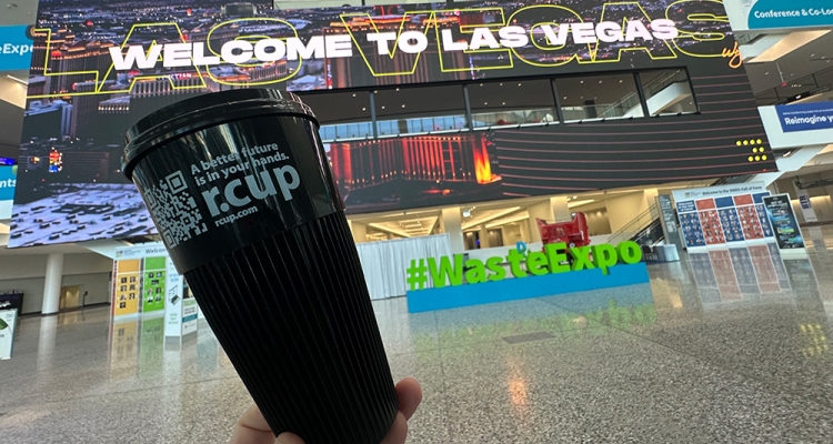 hand holding reusable cup in front vegas sign in expo hall