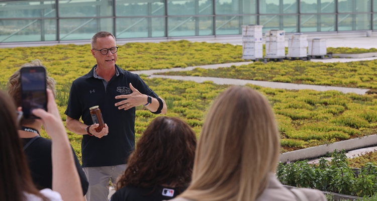 man speaks about beehives behind him