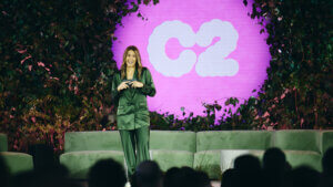 The woman with the C2 sign behind her is talking