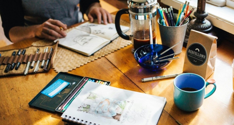 man working on sketchbook on table