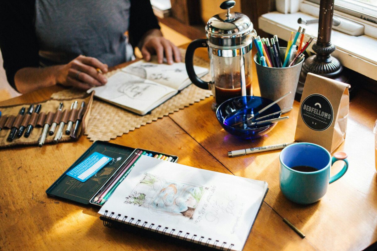 man working on sketchbook on table