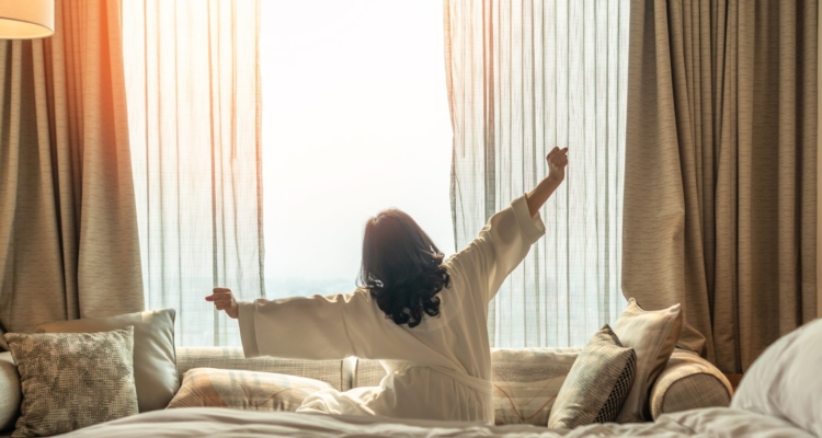 Woman waking up from a good nights sleep on bed