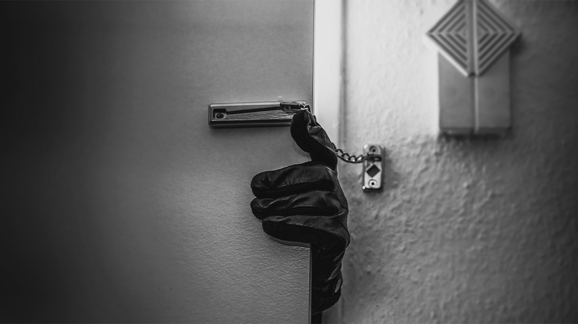 Black and white image of gloved hand holding door