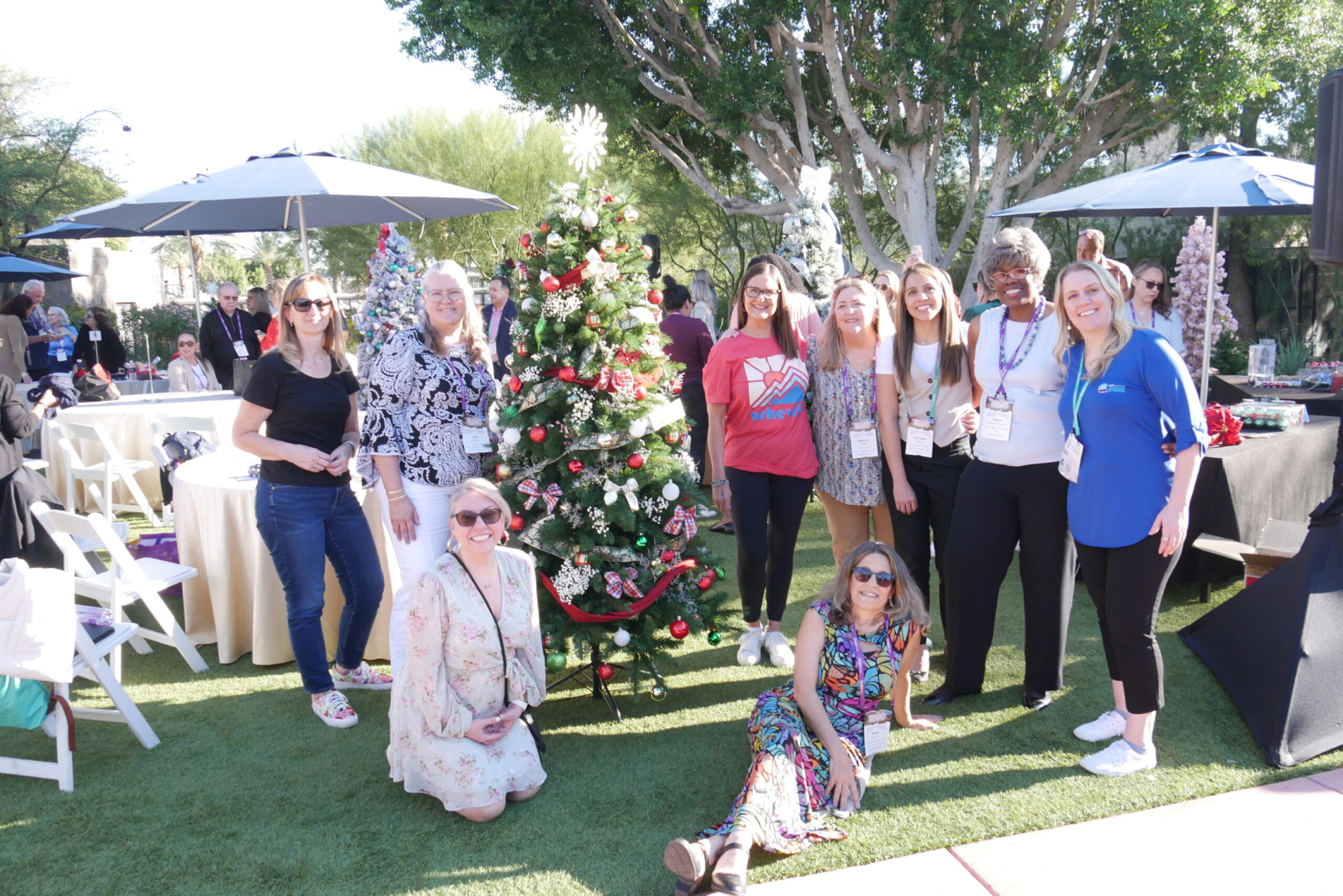 group of people standing next to decorated Christmas tree