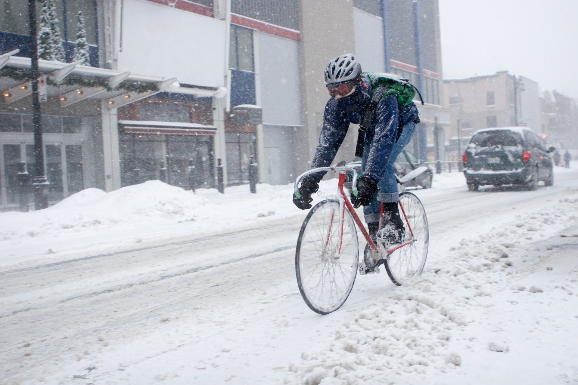 A man on a bicycle bikes through a snowy blizzard.