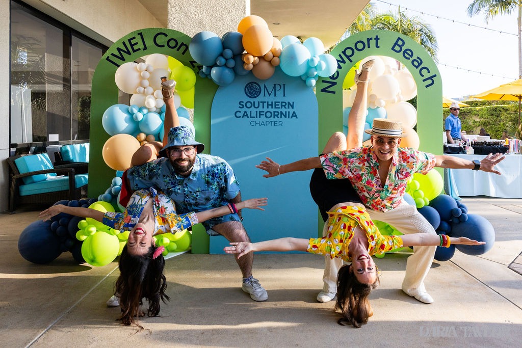 Two pairs of brightly dressed people spread their arms at the entrance to WeCon Southern California