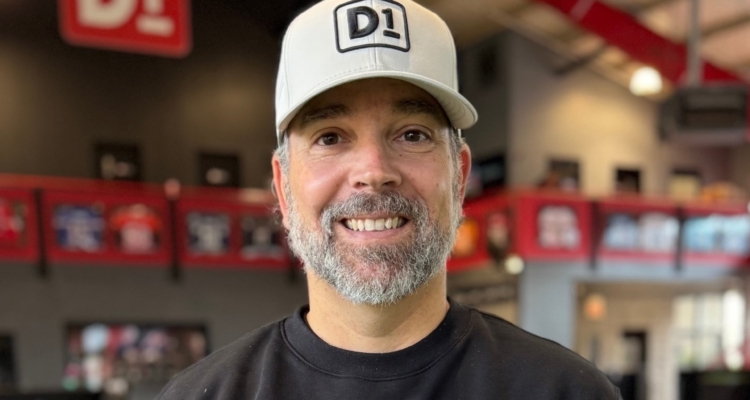 A photo of Dom Bonvissuto in a baseball cap and a black D1-branded sweatshirt.