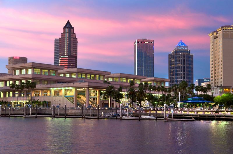 Sun setting over the downtown cityscape and the Tampa Convention Center along the Riverwalk.