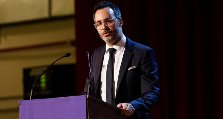 man with glasses speaking at podium