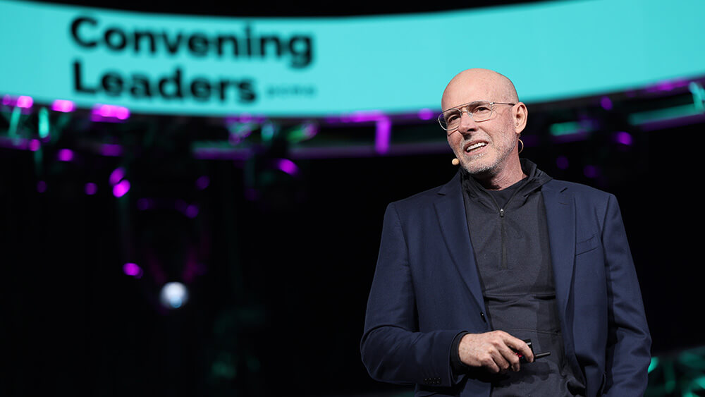 bald whit man with glasses smiling on stage